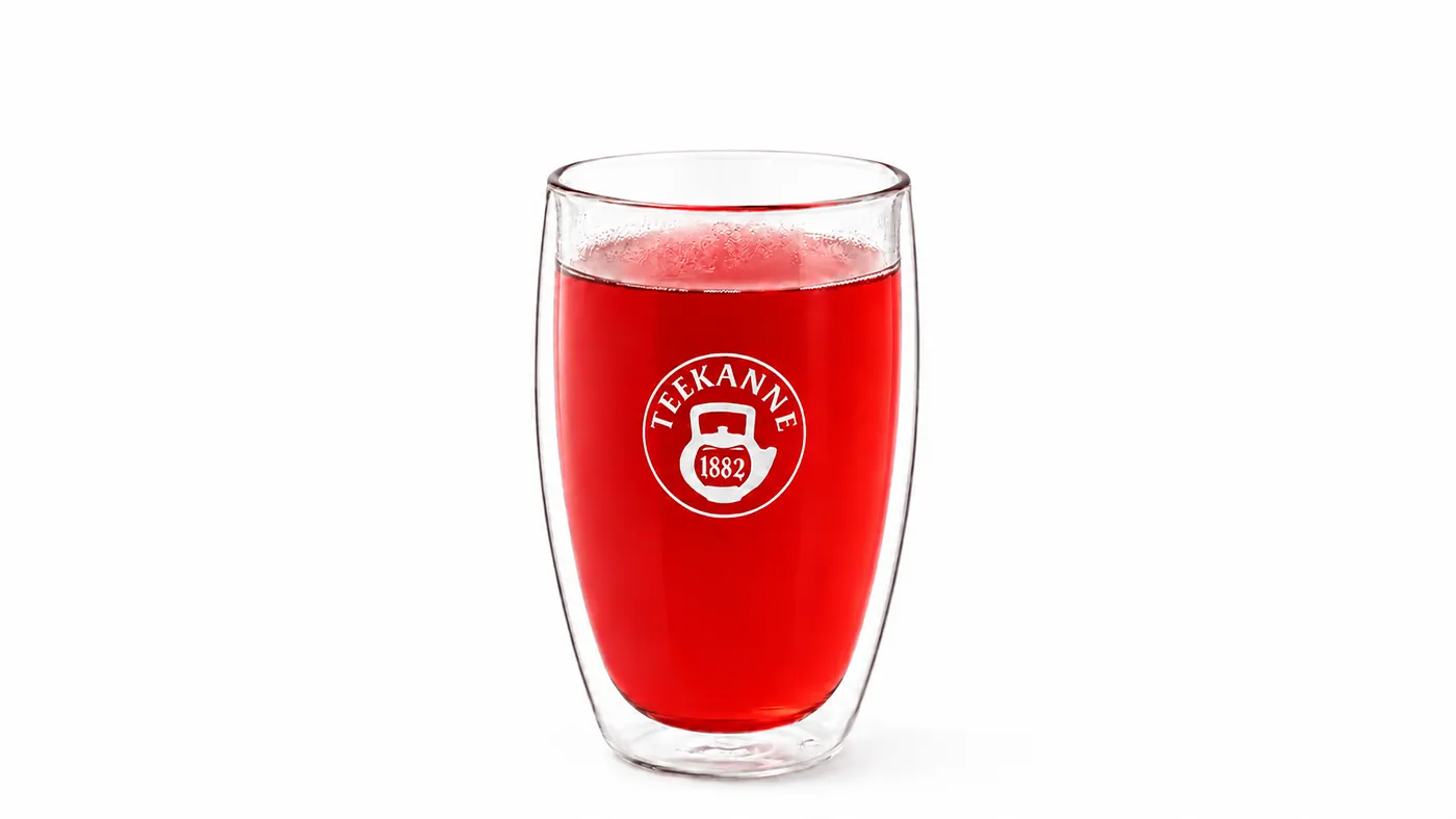 A red TEEKANNE tea infusion in a modern glass on a white background.
