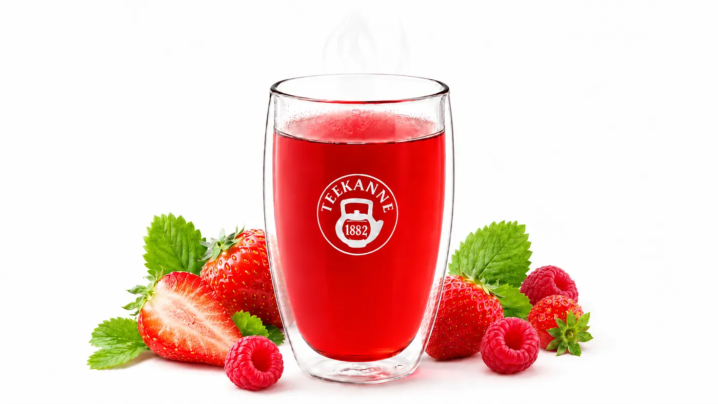 A red TEEKANNE tea infusion surrounded by strawberries, raspberries and green leaves.